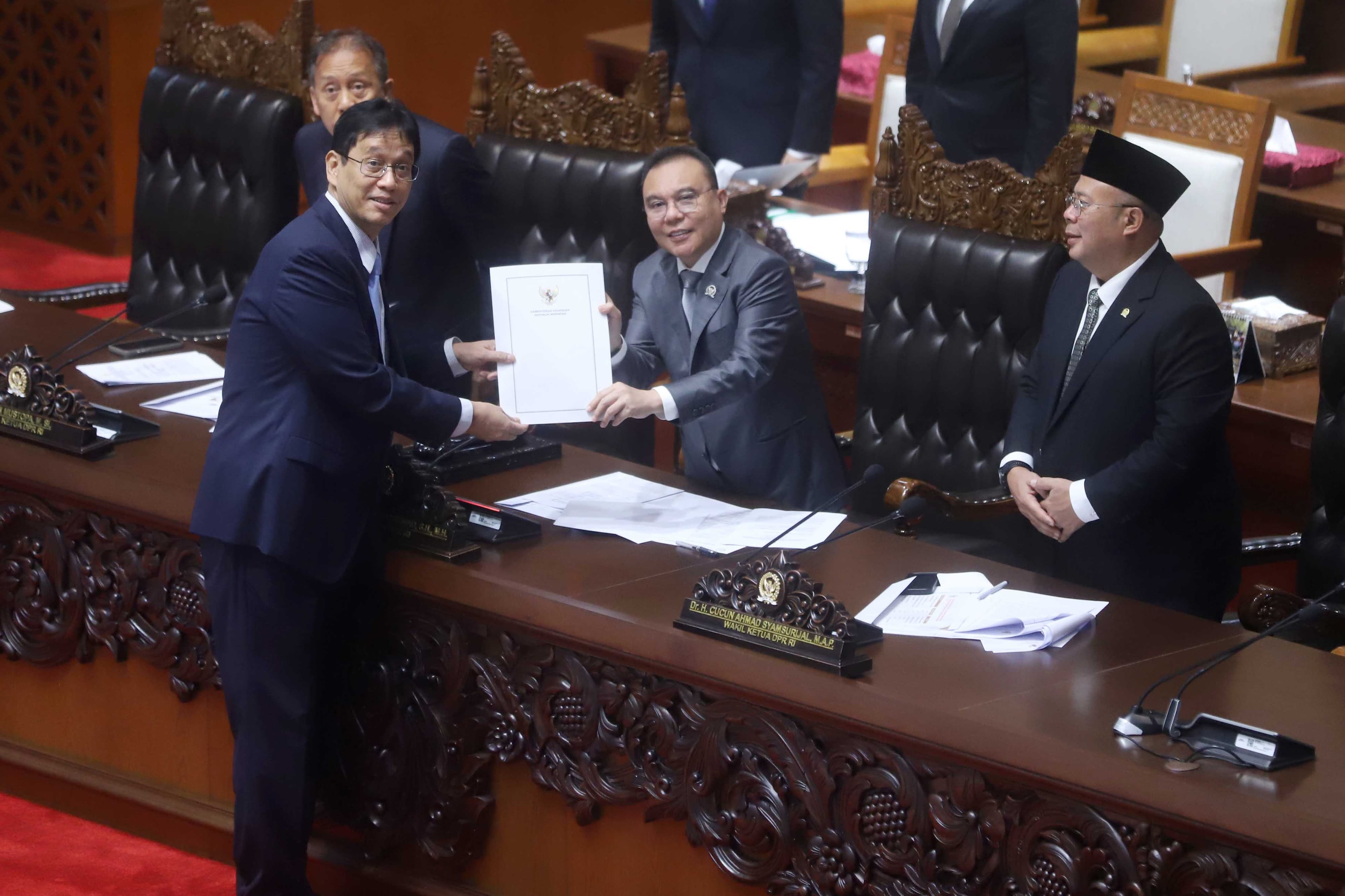 Menteri Keuangan Purbaya Yudhi Sadewa (kiri) menyerahkan berkas pendapat akhir kepada Wakil Ketua DPR Sufmi Dasco Ahmad (tengah) dan Cucun Ahmad Syamsurijal (kanan) saat Rapat Paripurna DPR di Kompleks Parlemen, Senayan, Jakarta, Kamis (4/6/2026). Dalam rapat tersebut, DPR menyetujui RUU Perubahan atas Undang-Undang Nomor 4 Tahun 2023 tentang Pengembangan dan Penguatan Sektor Keuangan (P2SK) menjadi Undang-Undang (UU).  AKURAT.CO/Sopian