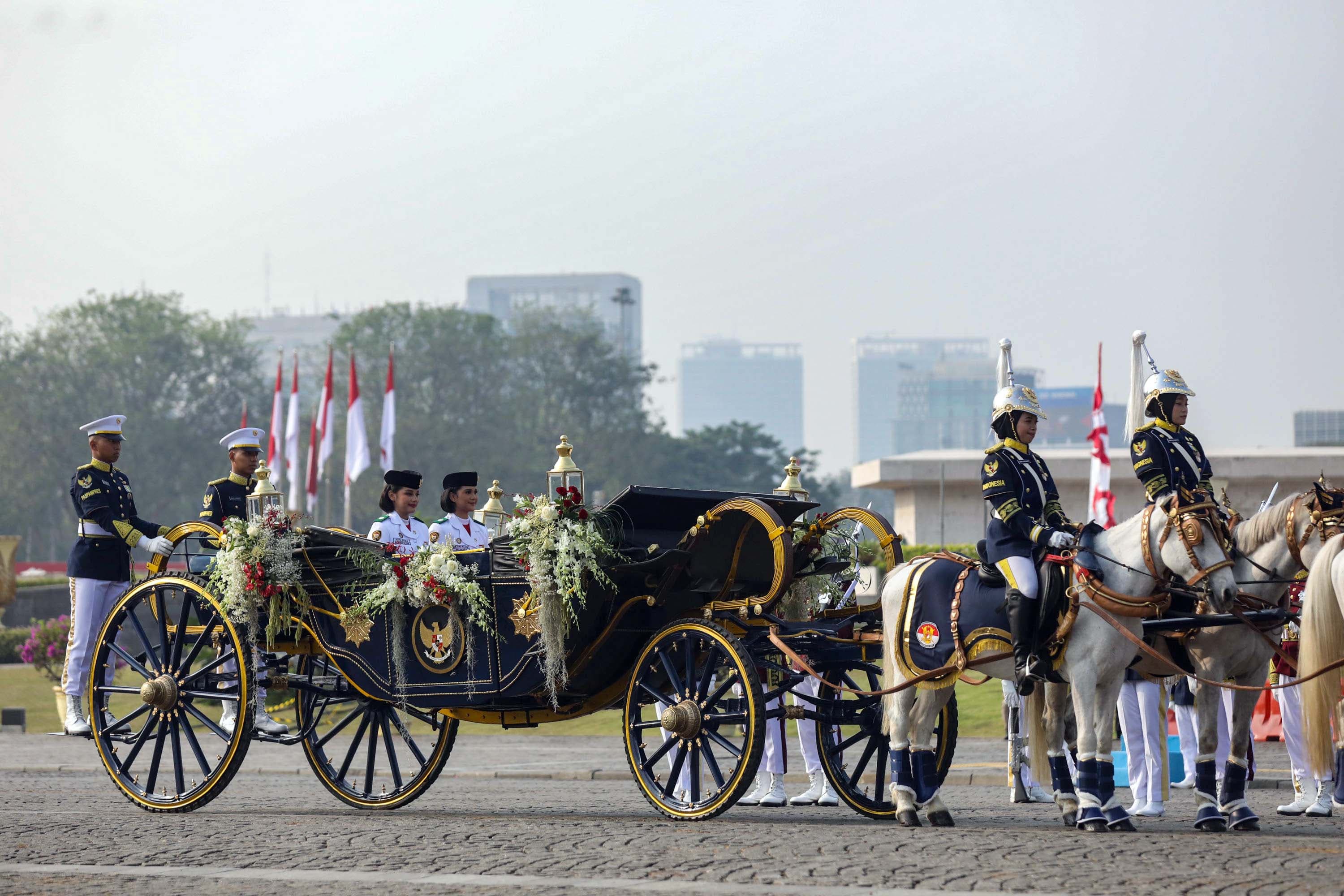 urna Paskibraka Duta Pancasila 2025 Bianca Sultana Najwa (kanan) dan Aliah Sakira (kedua kanan) membawa bendera pusaka dan naskah Proklamasi di atas kereta kencana Garuda Prabayaksa dari Monumen Nasional menuju Istana Merdeka dalam kirab Merah Putih di Jakarta, Senin (17/8/2026). AKURAT.CO/Endra Prakoso