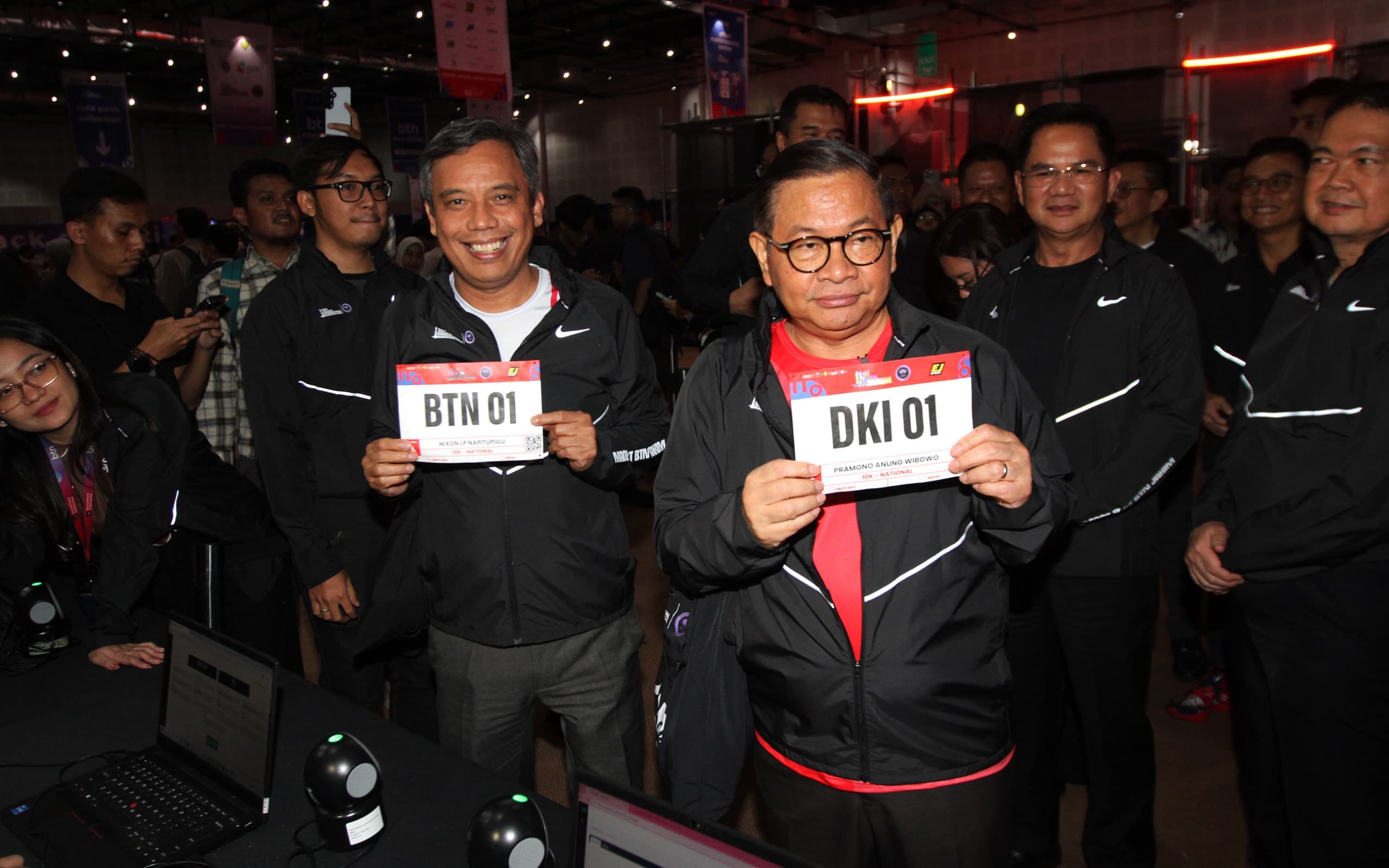 Direktur Utama PT Bank Tabungan Negara (Persero) Tbk (BTN) Nixon LP Napitupulu (kiri) bersama Gubernur DKI Jakarta Pramono Anung (kanan) menunjukkan body identification number (BIB) usai mengambil race pack